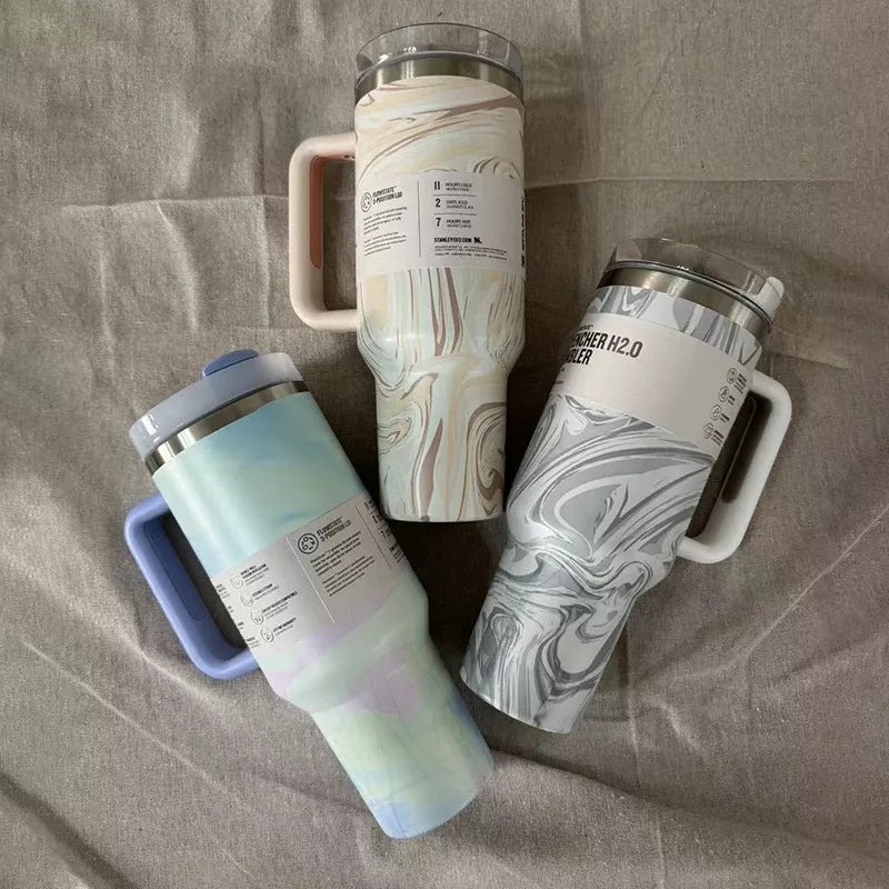Three insulated travel mugs with handle on a textured surface