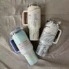 Three insulated travel mugs with handle on a textured surface