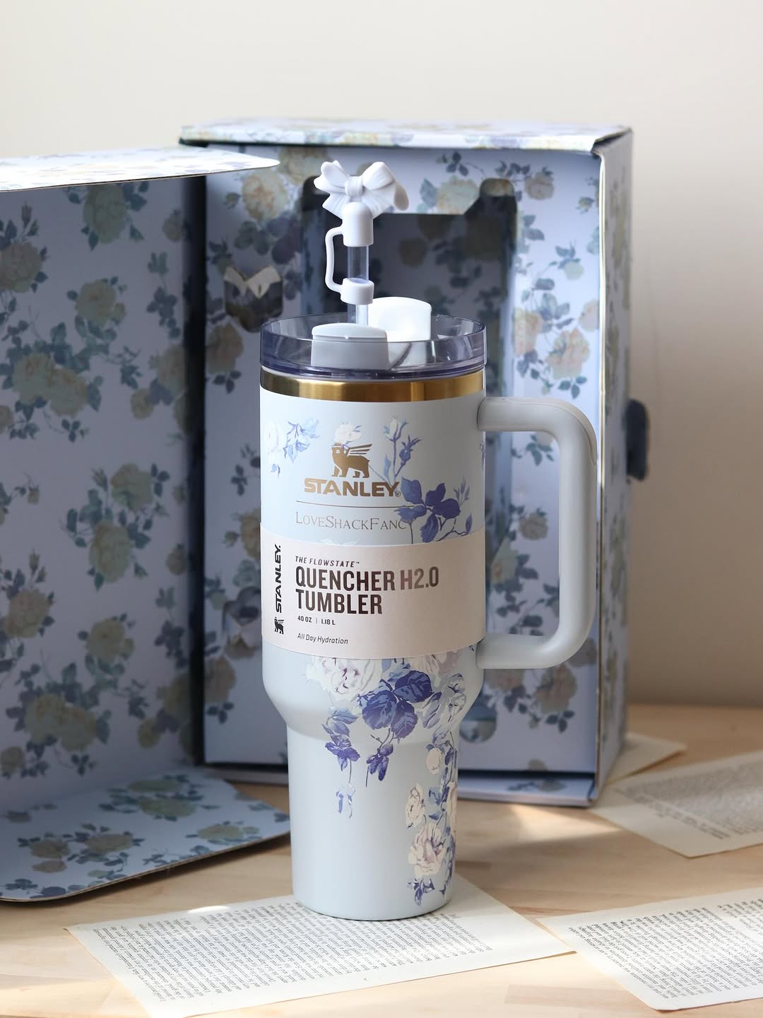Stanley tumbler with floral design in a floral-patterned box on a wooden surface.
