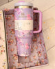 LoveShackFancy Stanley 40oz Tumbler in pastel floral pattern shown upright on outdoor picnic setting