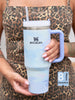 Person holding a Stanley mug with leopard print apron