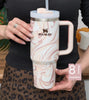 Person holding a marbled Stanley mug with a straw, wearing a leopard print skirt.