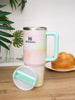 Stanley mug with a pastel gradient design on a wooden surface with a plant and bread in the background.