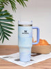 Stanley mug with a gradient design on a wooden surface with a plant in the background