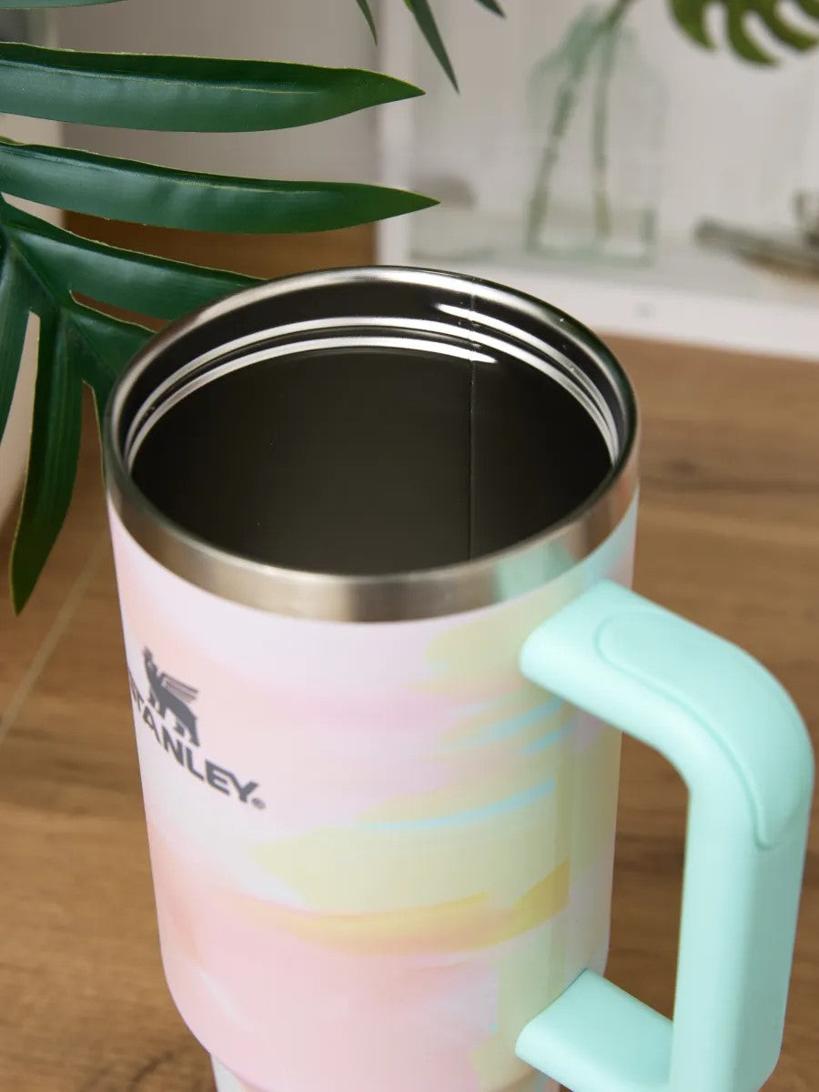Stanley mug with pastel design and green handle on a wooden surface
