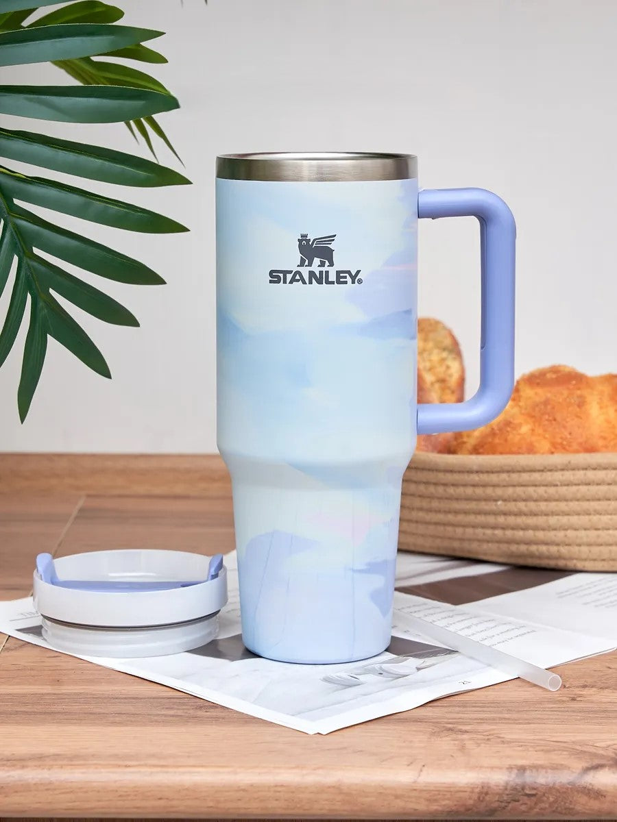 Stanley mug with gradient design on a wooden table with bread and a plant in the background