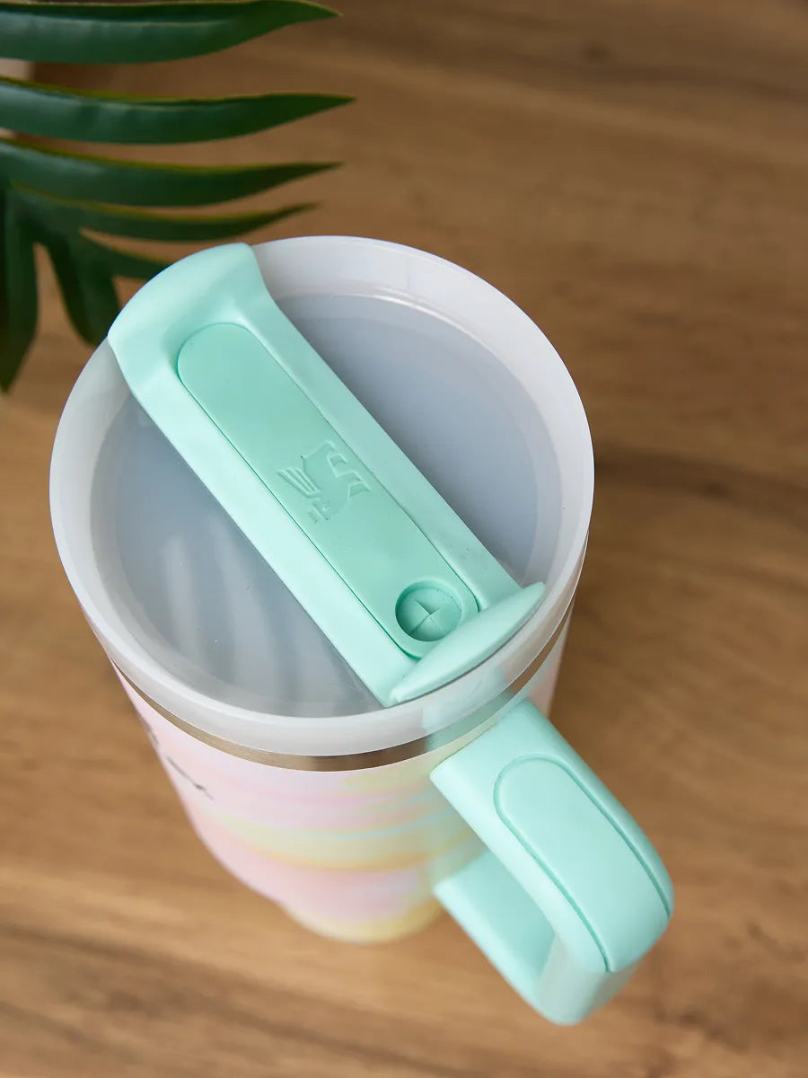 Colorful mug with a green handle and lid on a wooden surface