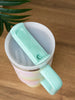 Colorful mug with a green handle and lid on a wooden surface