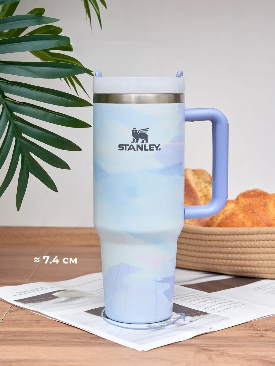 Stanley mug with gradient design on a wooden surface with a plant in the background